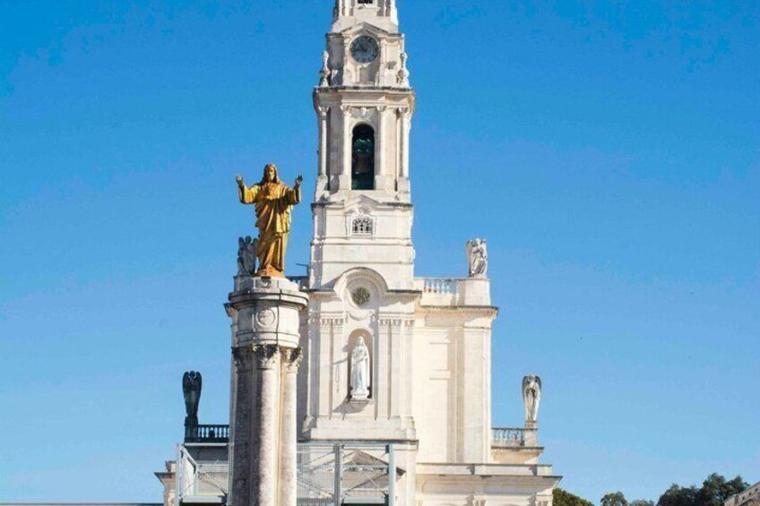 A white church with a tall bell tower and a golden statue on top. 1
