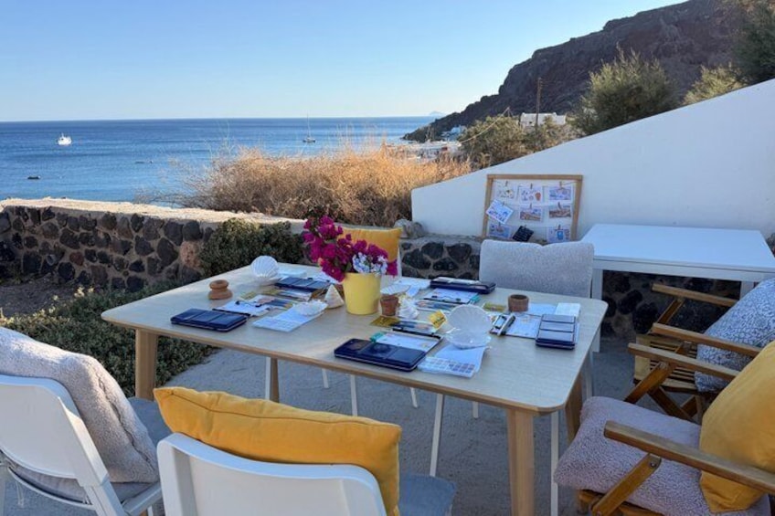 Tavolo apparecchiato su un patio con vista sull'oceano, una parete in pietra, sedie e panorama sul mare. 2