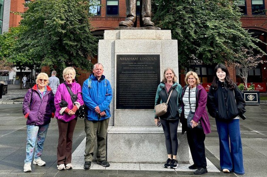 A group of people standing in front of a monument with a plaque. 4