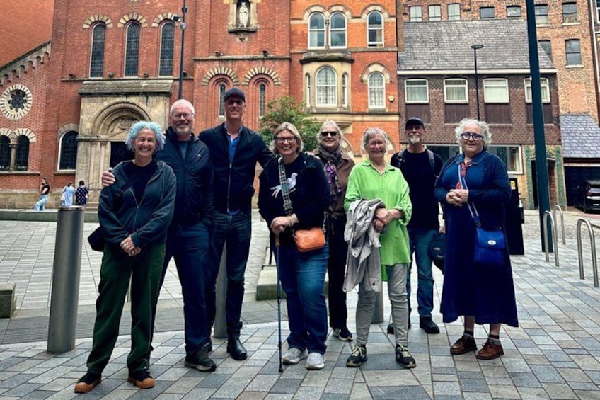 A group of people standing in front of a historic building with arched windows and a clock. 5