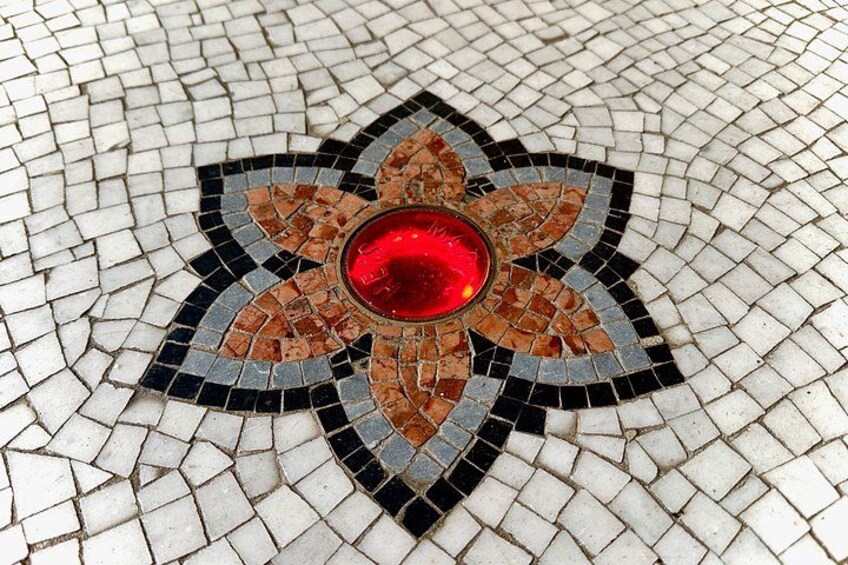 A mosaic tile floor with a central red circular design surrounded by a geometric pattern. 2