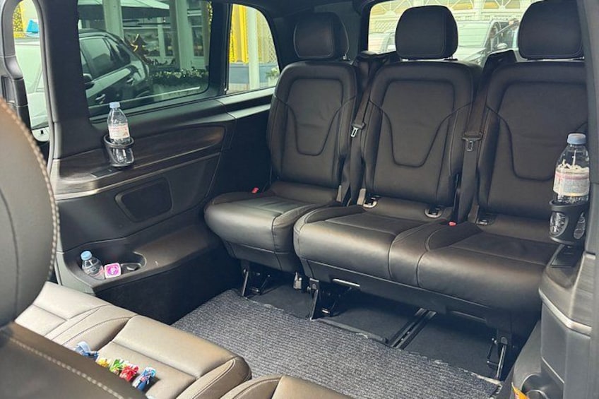 A vehicle's rear seating area with black leather seats, a rearview mirror, and a water bottle on the passenger seat. 2