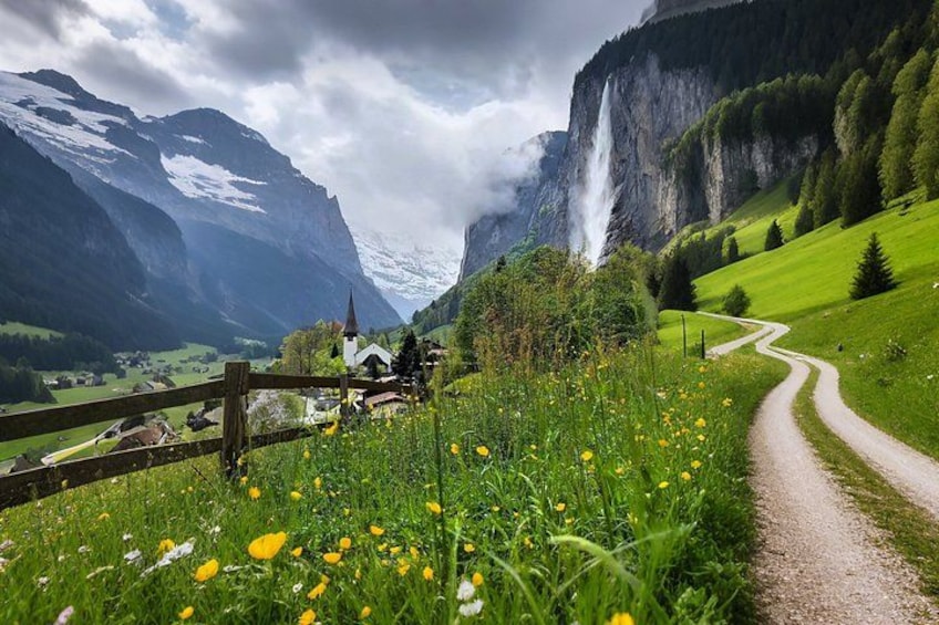 A mountainous landscape with a church, a waterfall, and a dirt path. 1
