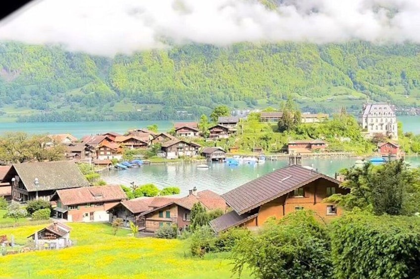 A lakeside village with traditional houses, a prominent castle, and lush greenery. 4