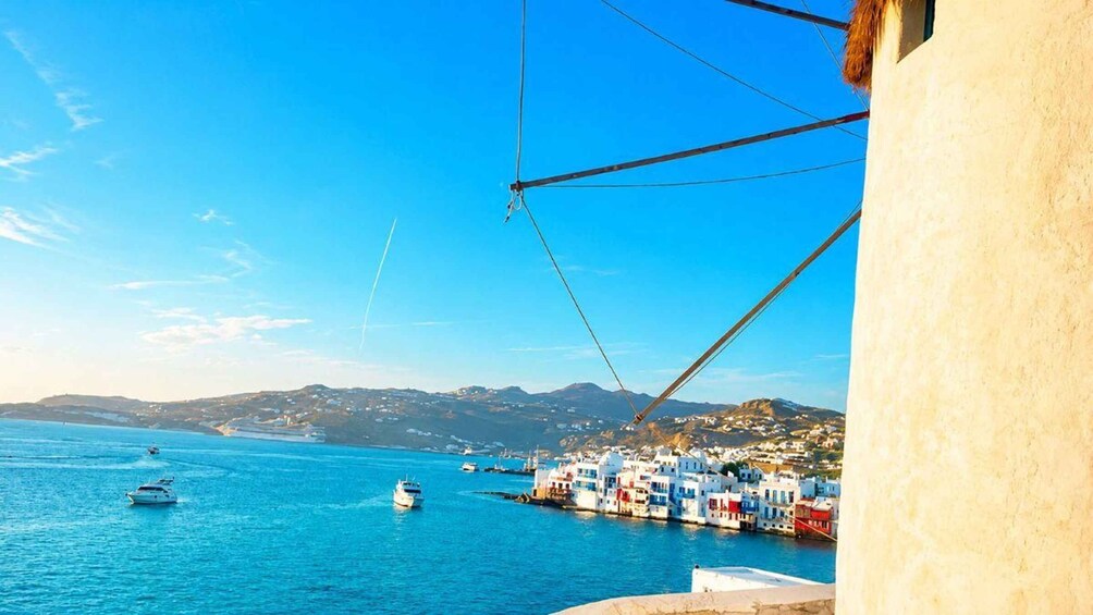 A coastal town with boats on the sea, a clear sky, and a mountainous backdrop. 2