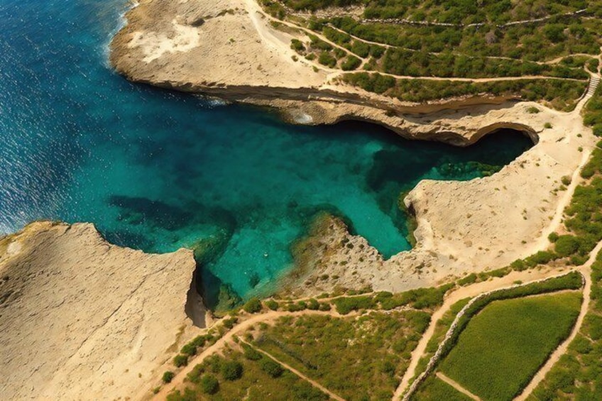 An aerial view of a coastal landscape with clear turquoise waters, a rocky shoreline, and green vegetation. 2