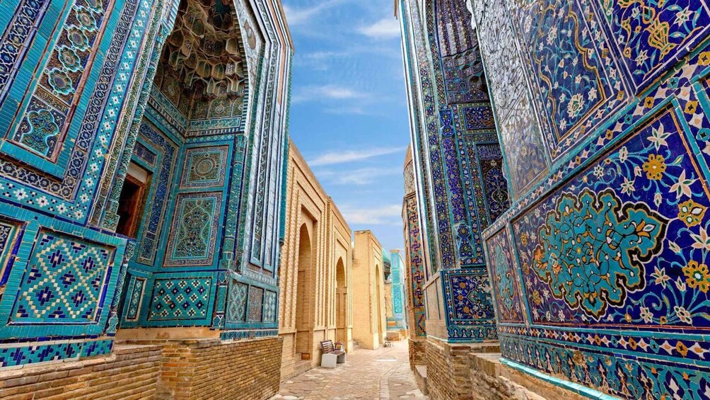 A narrow alley with ornate blue and turquoise tile work on the walls and arches. 4