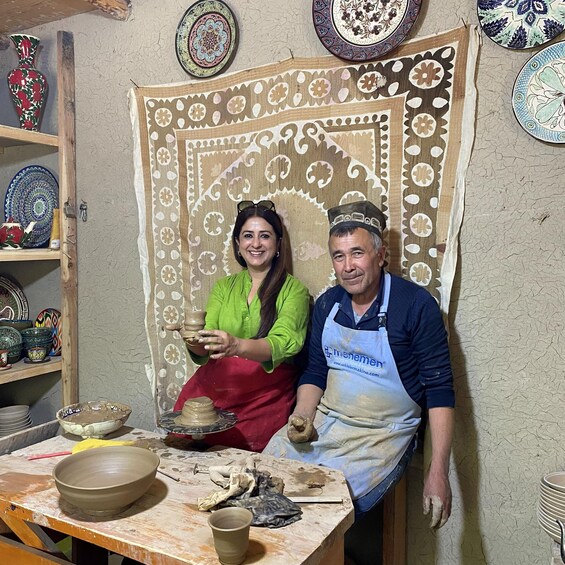 Two people in a pottery workshop with clay pots and decorative plates on shelves. 5