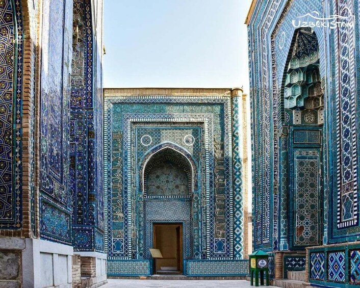 A courtyard with intricate blue and turquoise tile work, a central archway, and a building with similar decorative patterns. 2