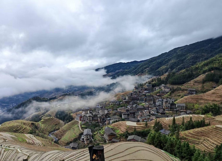 Terraced rice fields, traditional houses, and a mountainous landscape with clouds. 4