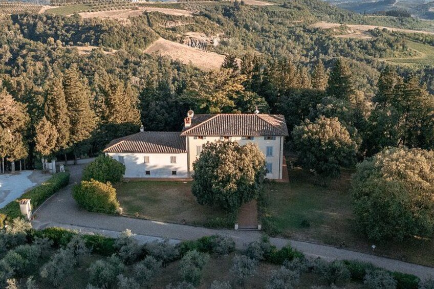 Une maison blanche avec un toit en tuiles, entourée d’arbres et située dans un paysage vallonné. 3