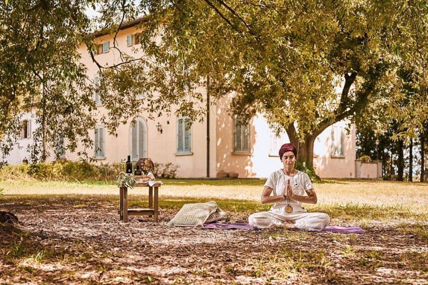 Une personne médite sous un arbre dans un parc, avec un bâtiment en arrière-plan. 1