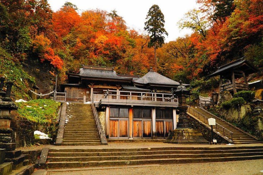 A traditional Japanese building with a wooden structure, surrounded by a stone staircase and autumn foliage. 4