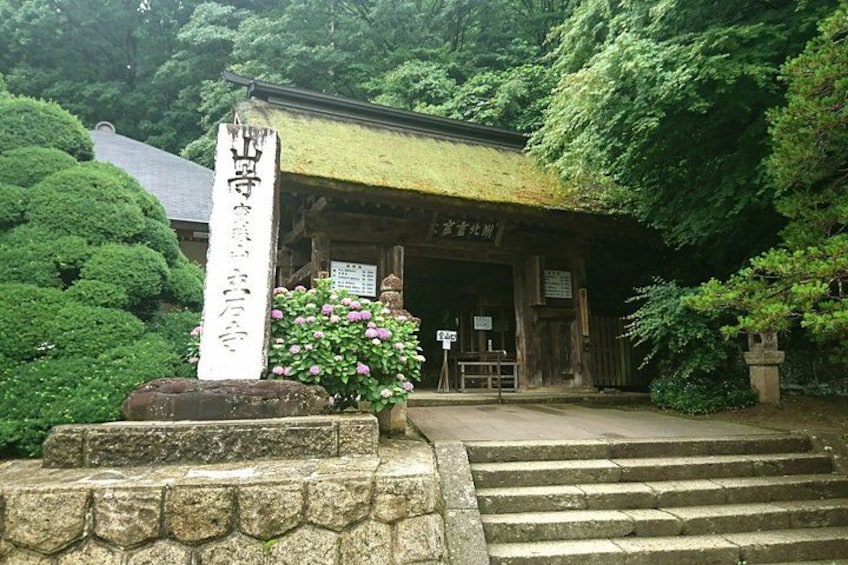 A traditional Japanese shrine with a stone lantern, steps leading up to the entrance, and lush greenery. 2