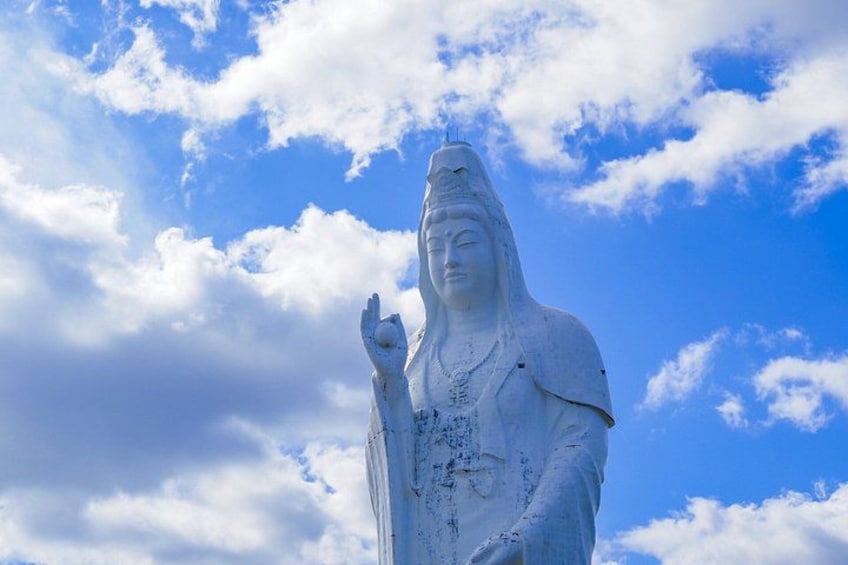 A large white statue against a blue sky with clouds. 3