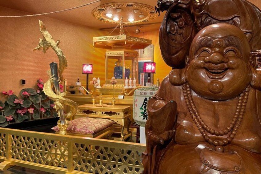 A traditional Chinese room with a large wooden statue of a laughing Buddha, a golden dragon sculpture, and a mirror reflecting the room's interior. 2