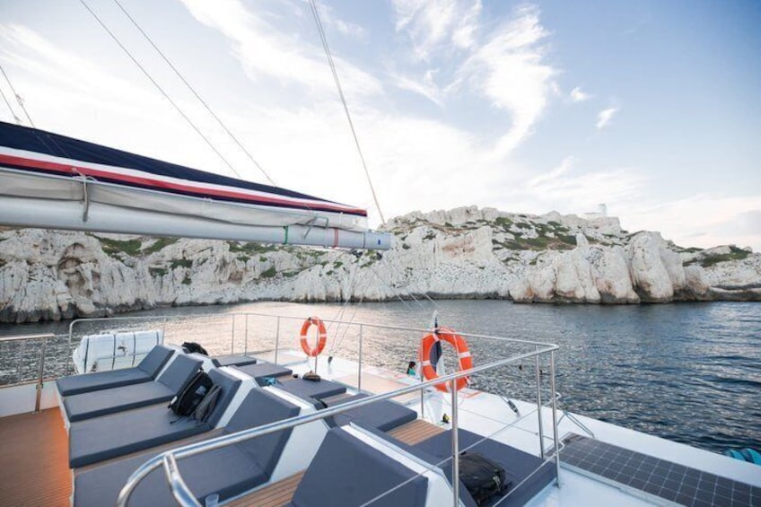 A boat deck with life jackets, a railing, and a rocky coastline in the background. 4