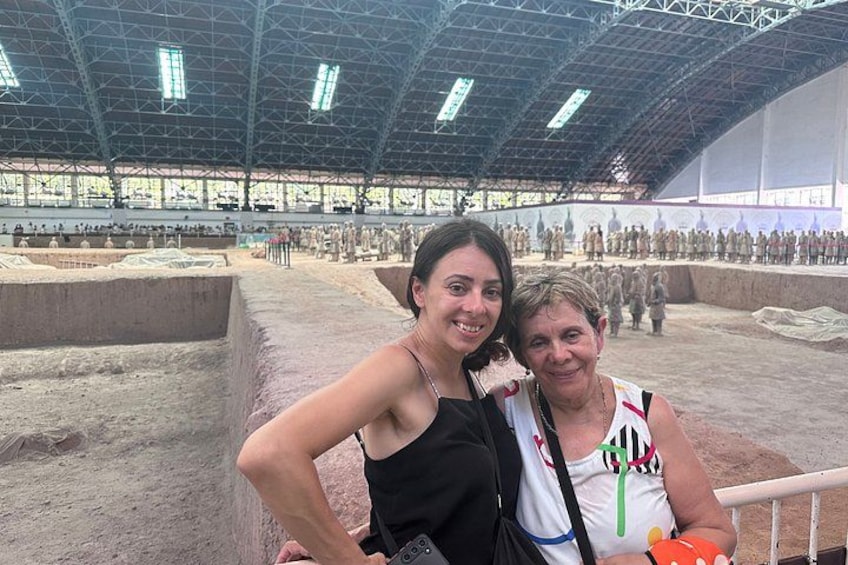 An indoor archaeological site with a large open space, a stage, and a crowd of people. 3