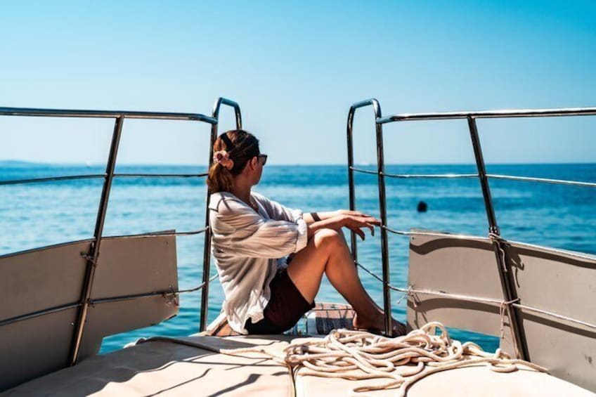 A person sitting on a boat deck with a view of the sea. 3