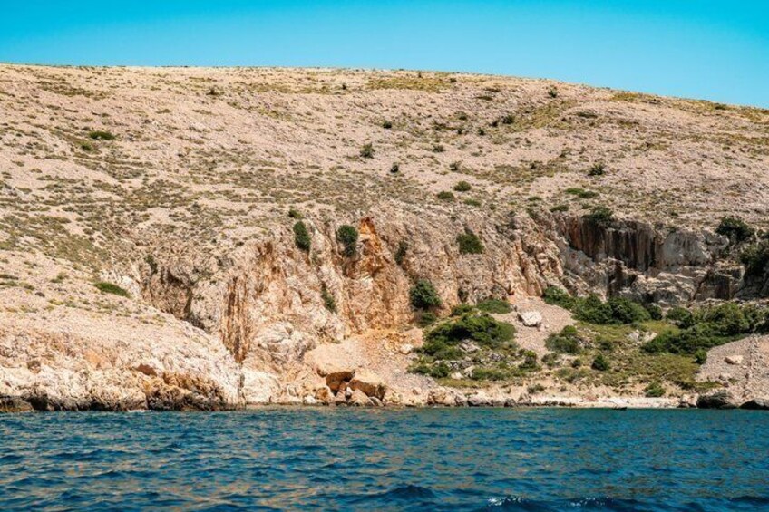 A coastal landscape with rocky cliffs and sparse vegetation. 2