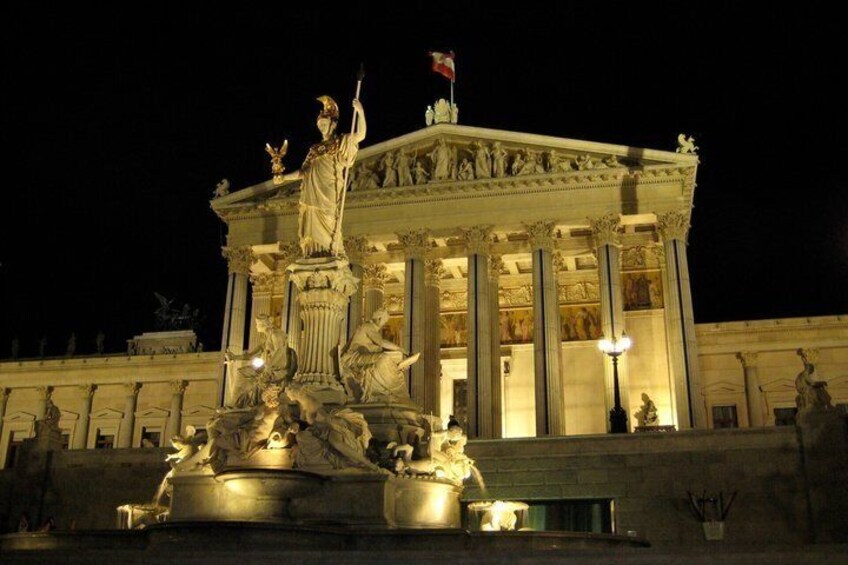 Un bâtiment de style classique, orné d’une statue représentant une figure tenant un bâton, et entouré d’une fontaine agrémentée de sculptures. 1