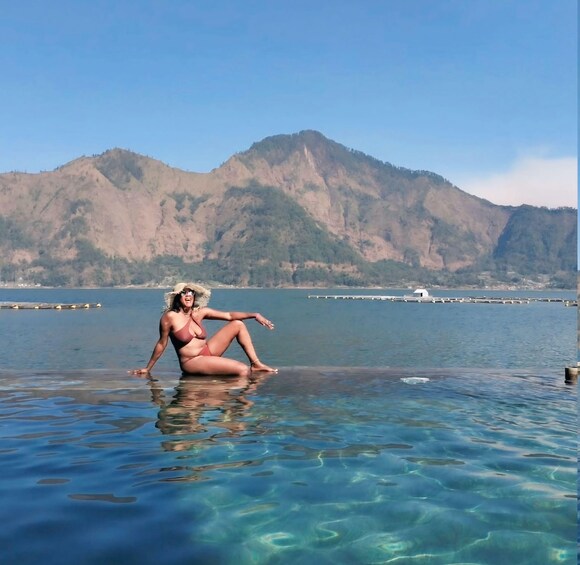 A person sitting on a clear water body with mountains in the background. 3