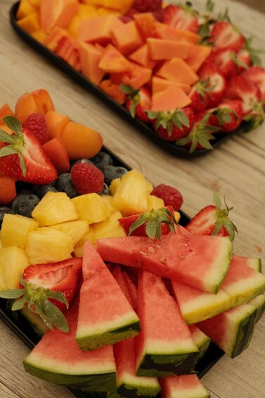 Two trays of assorted fresh fruits including watermelon, strawberries, blueberries, pineapple, and cantaloupe. 3