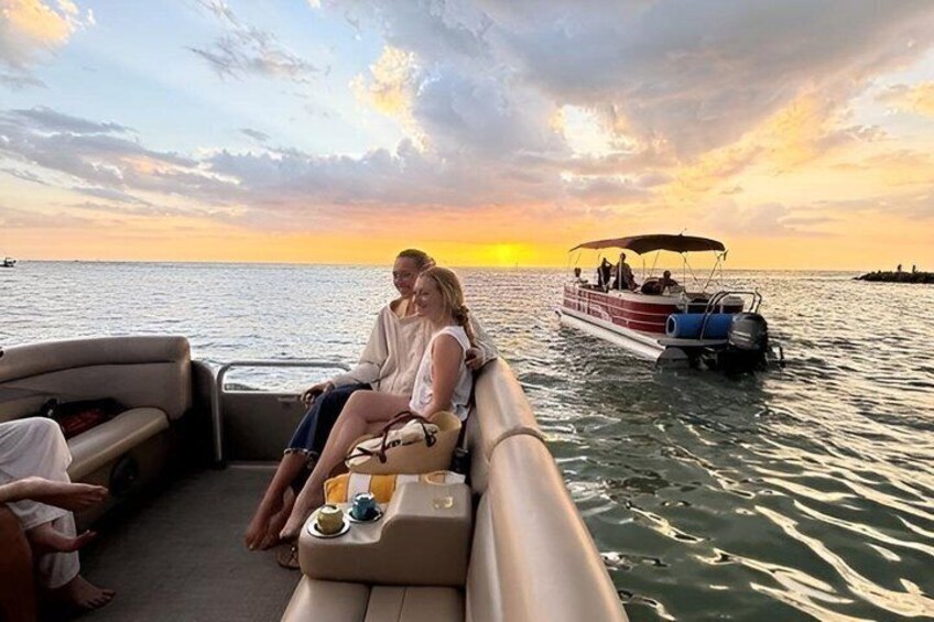A sunset over water with a boat and people on a dock. 4