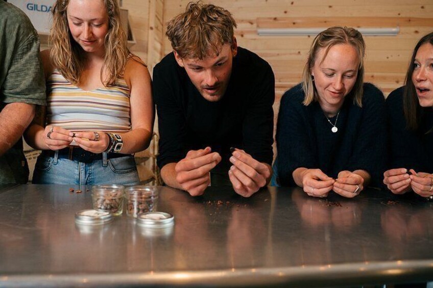A group of people seated at a table with glasses and a bottle, possibly engaged in a tasting or drinking activity. 2