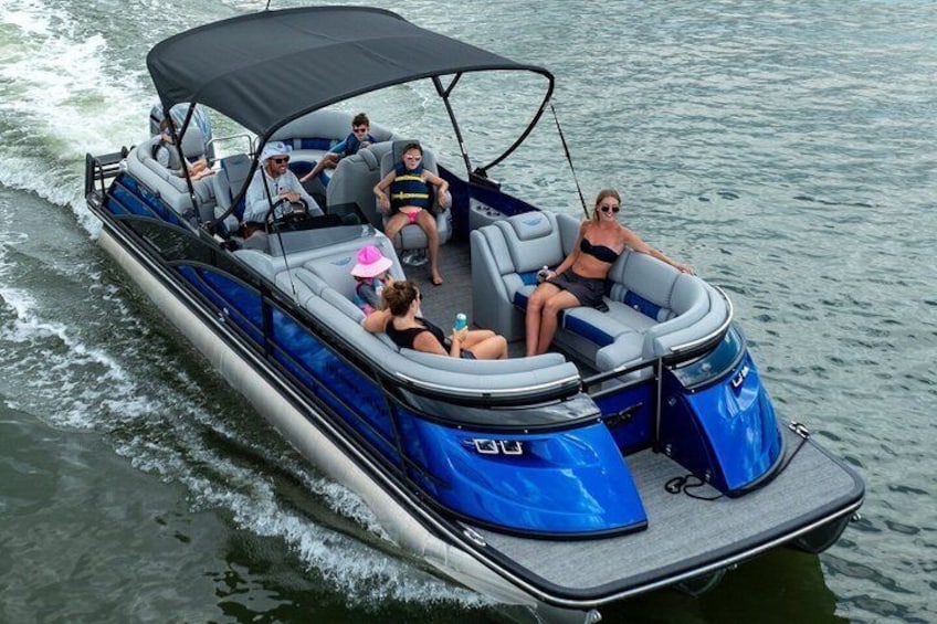 A blue and white motorboat with a canopy, carrying several people on a body of water. 1