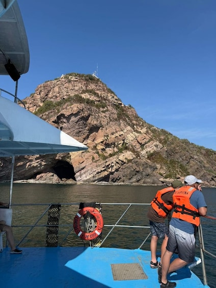 En båd med mennesker i redningsveste, en klippe og en redningskrans på dækket. 5