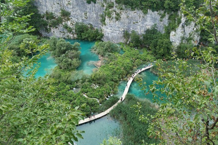 A suspension bridge over turquoise waters, surrounded by dense greenery and cliffs. 1