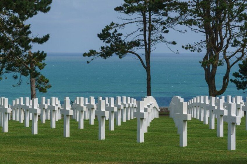 A cemetery with white crosses and a view of the ocean. 2