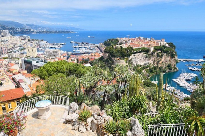 A coastal city with a historic castle on a cliff, marina, and lush greenery. 3