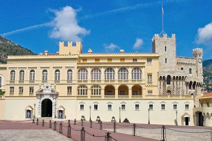 A large historic building with a prominent tower, a central archway, and a paved courtyard. 5