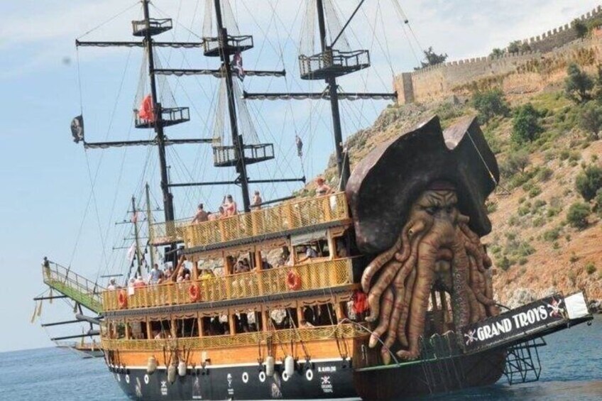 Een piratenthema boot met een groot octopus-figuurprent, passagiers en een kustachtergrond. 3