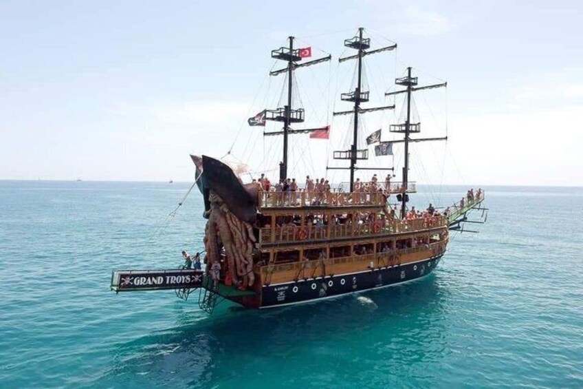 Een groot schip met meerdere dekken en vlaggen, zeilend over een rustige zee. 2