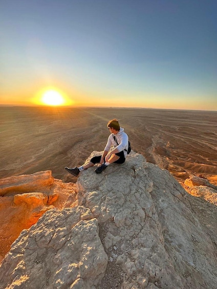 A person sitting on a rock with a sunset in the background. 5