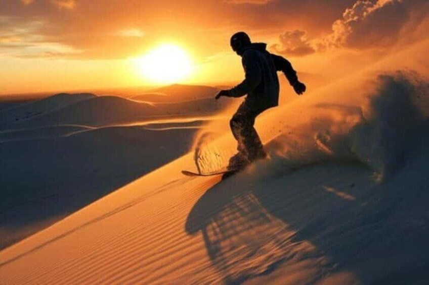 Un snowboardeur effectuant un virage sur une pente enneigée au coucher du soleil. 3
