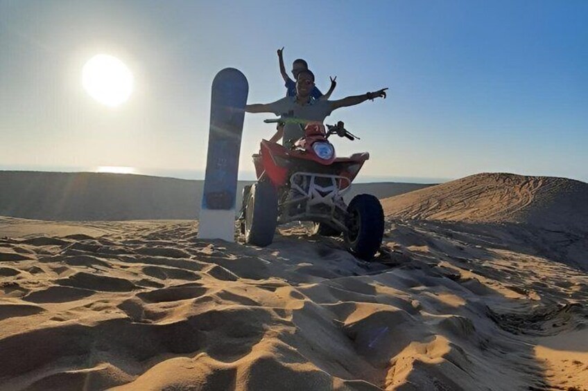Une personne sur un quad, avec une planche de snowboard, dans le désert au coucher du soleil. 4