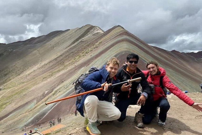 Three people on a mountain with a colorful rock formation in the background. 1
