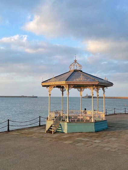 A gazebo with ornate metalwork by the seaside. 2