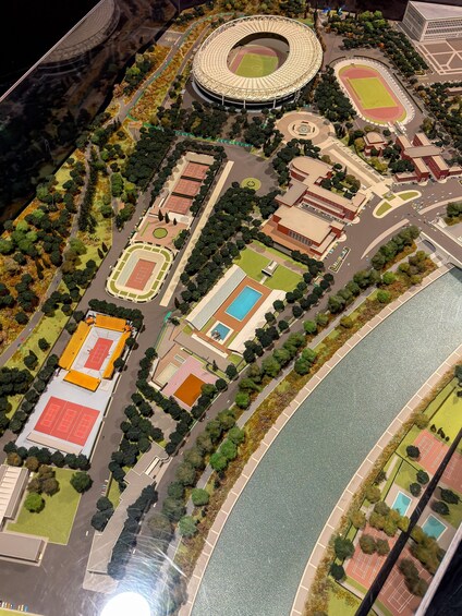 A detailed model of a sports complex with a stadium, tennis courts, and a river. 3