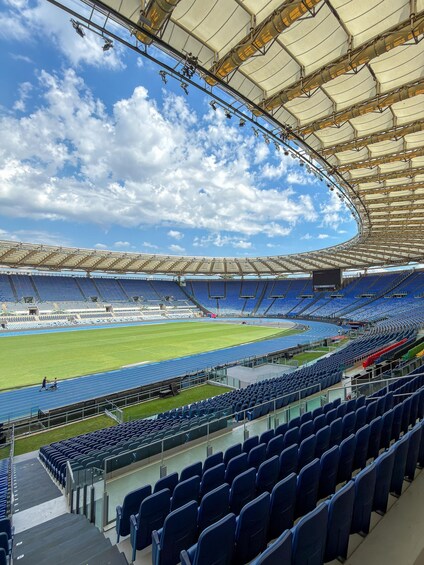 A large, empty stadium with blue seats and a track. 4