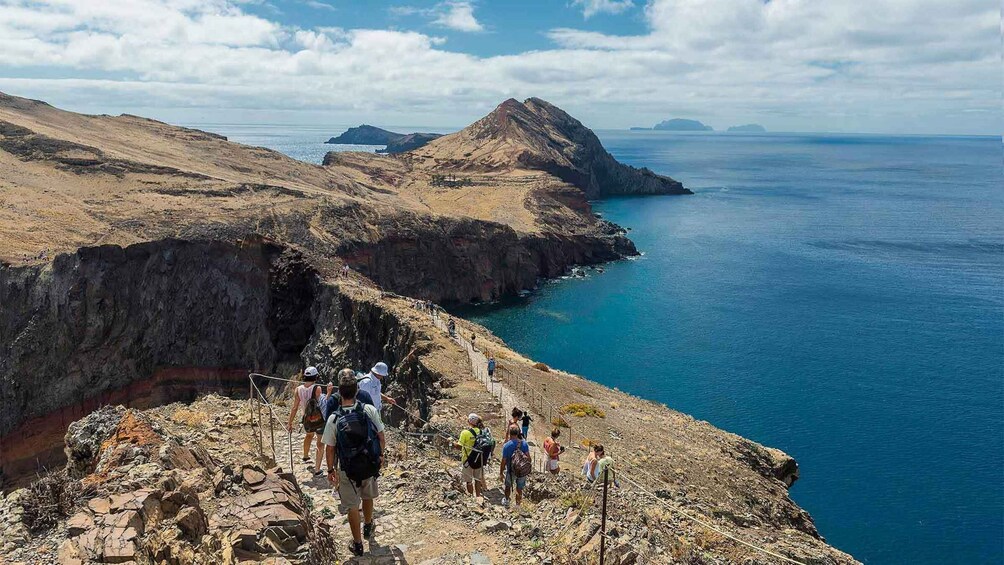 A rocky coastal landscape with hikers on a trail. 3