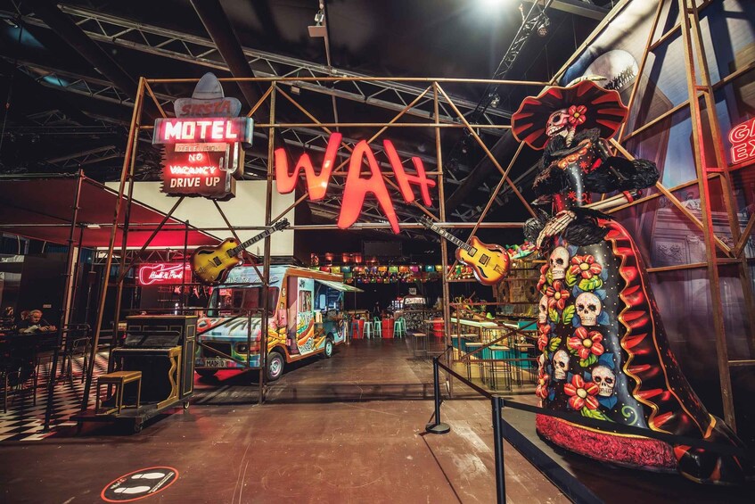 A vibrant indoor venue with a neon sign reading 'Motel Wah' and a large decorative figure. 1