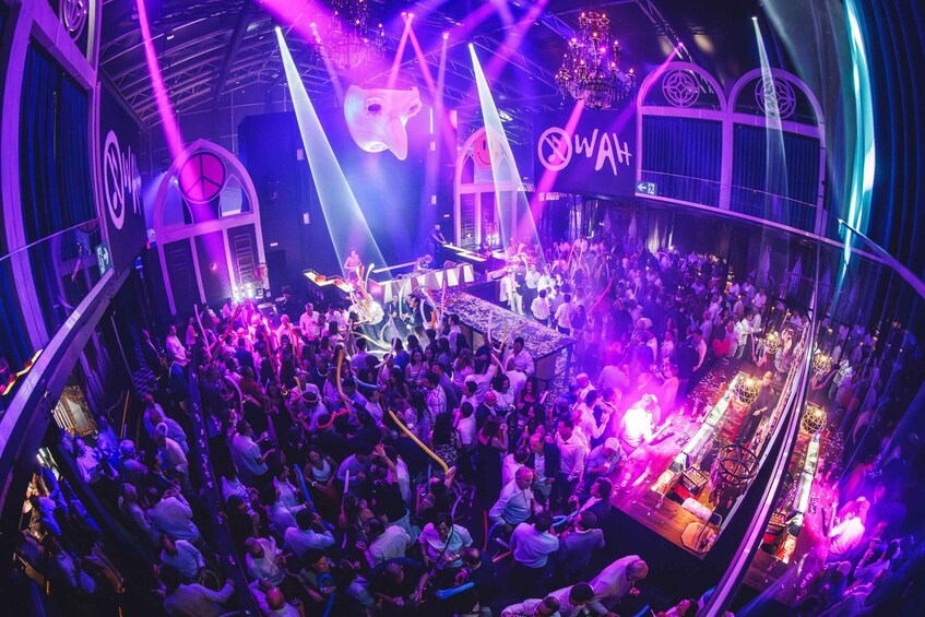 A crowded nightclub with a DJ booth, purple lighting, and a 'Watt' sign. 2