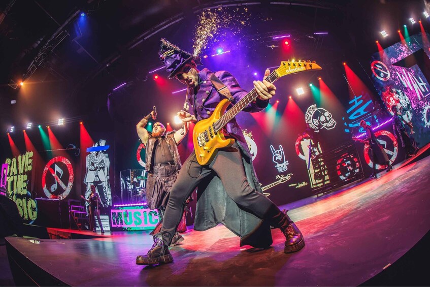 A band performing on a stage with a vibrant, illuminated backdrop and a dynamic lighting setup. 5