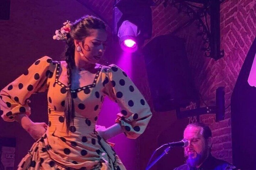 A person in a polka dot dress performing on stage with a microphone stand in the background. 3
