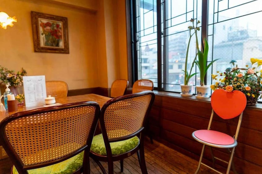 A restaurant interior with wicker chairs, a wooden table, and a window with city views. 5